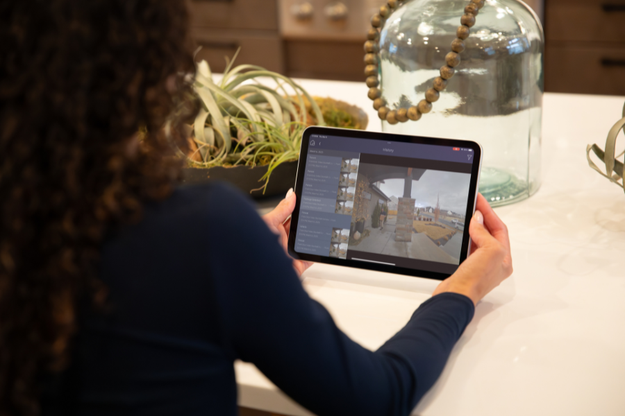 Person using a tablet to view security camera footage in a modern home, highlighting remote monitoring and easy access to smart home surveillance systems.